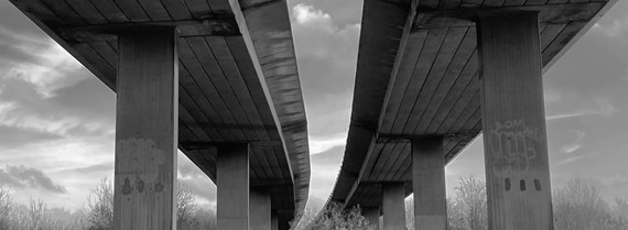 The view from below of two motorway bridges parallel to each other and a cloudy sky