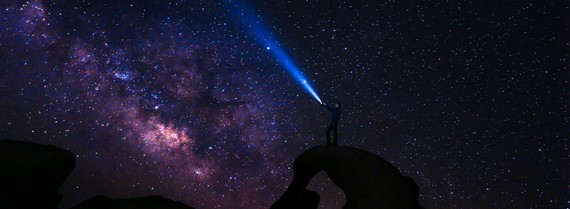 Person shining light at the night sky full of stars